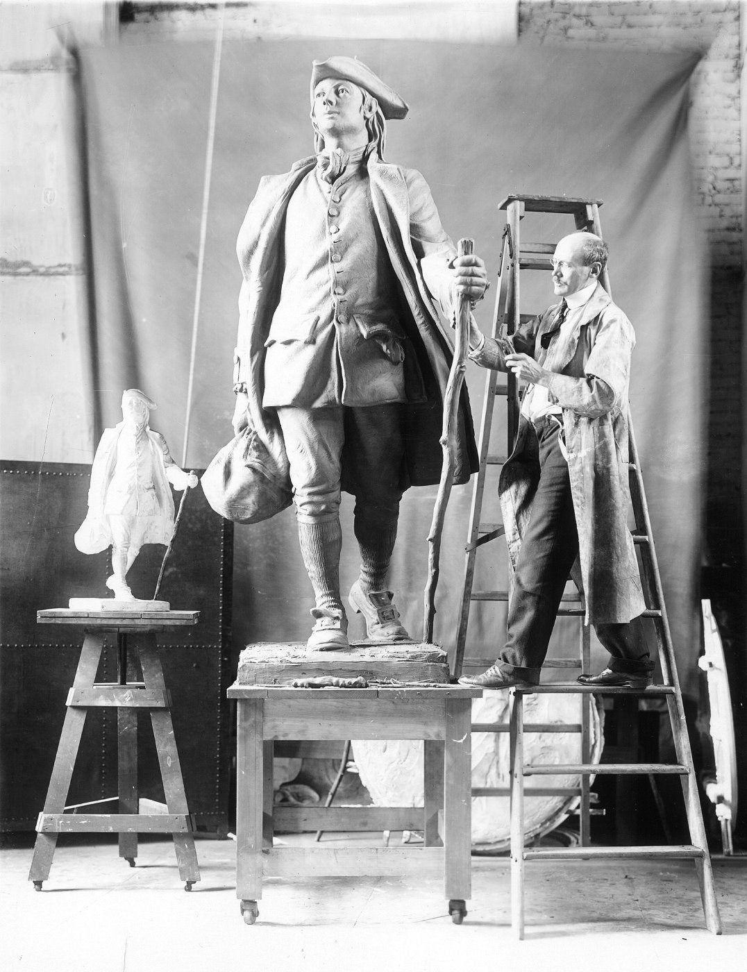 R. Tait (Robert Tait) McKenzie at work in his studio on his sculpture of young Benjamin Franklin, 1911